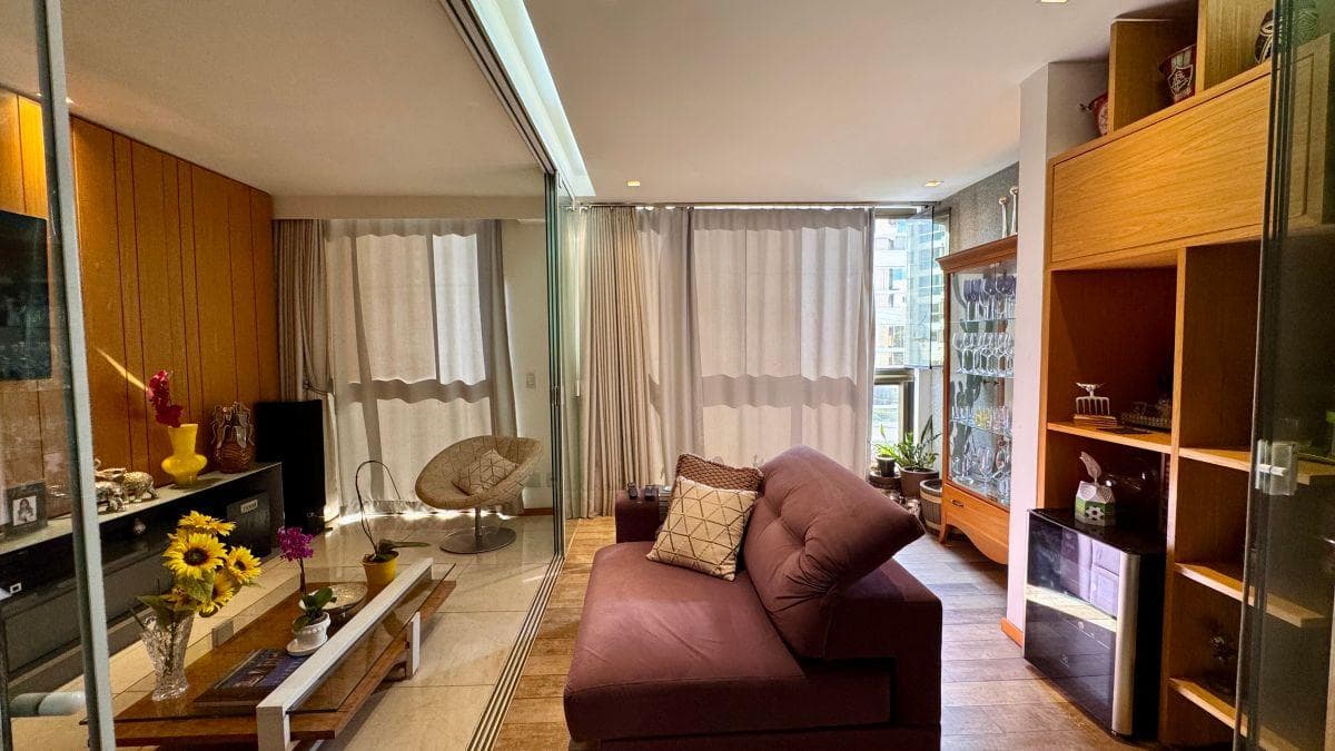 Sala integrada com painel de TV, sofá e estante em madeira.