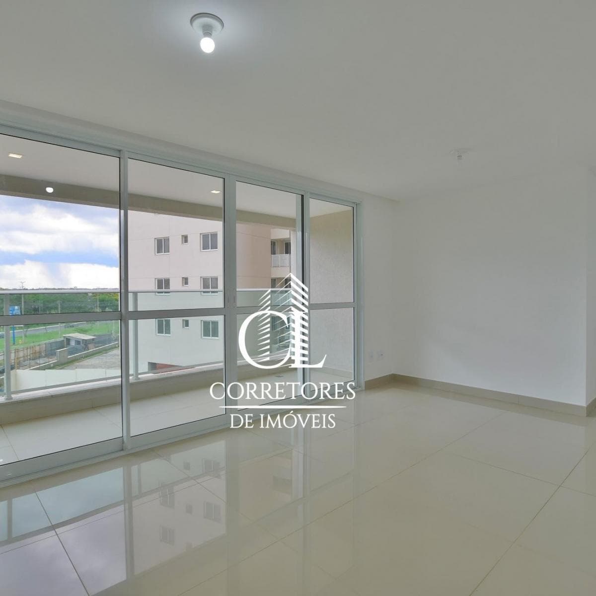 Sala iluminada com piso revestido em porcelanato claro e grandes janelas de vidro com vista externa.