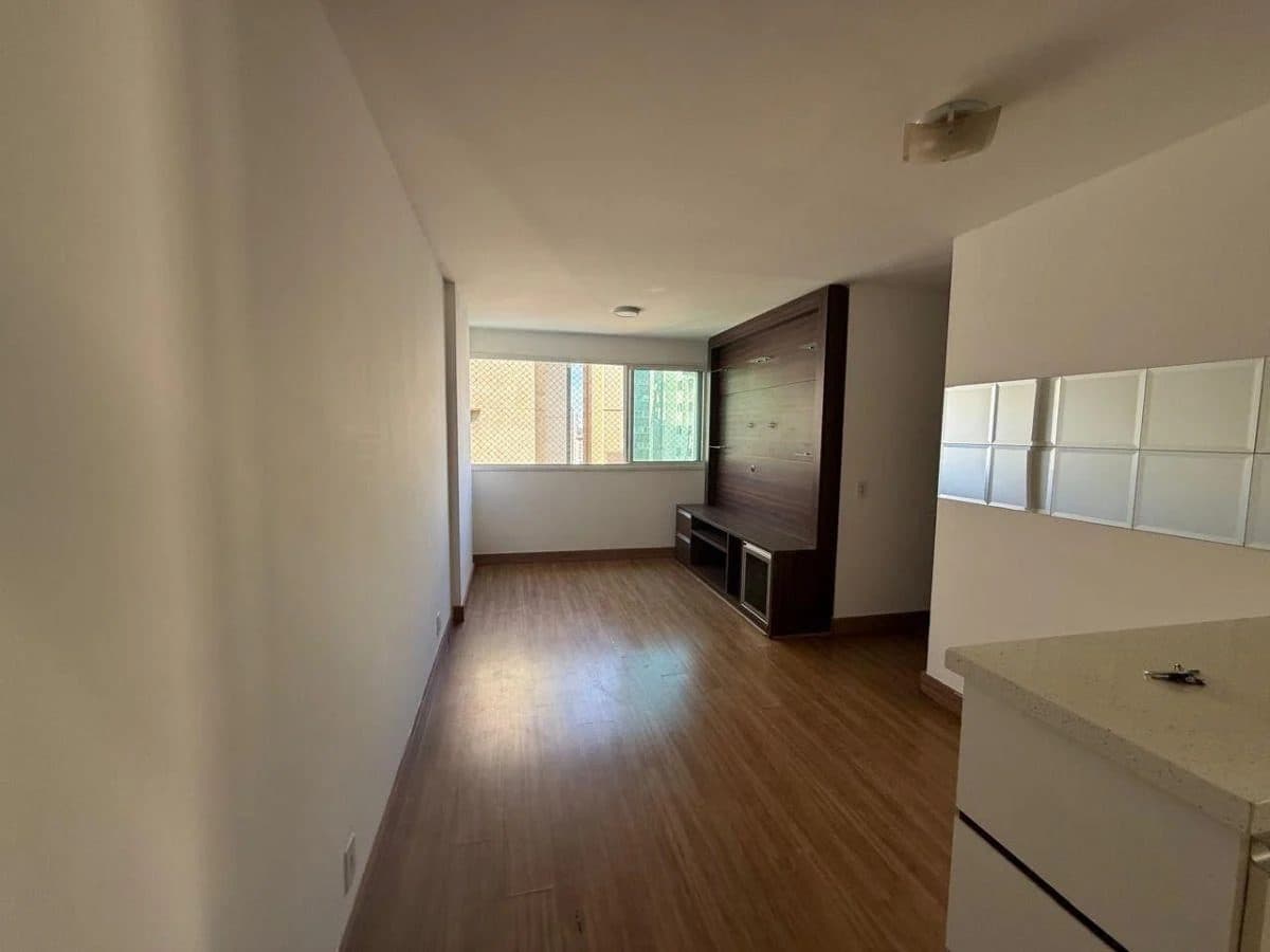 Sala de estar com piso amadeirado, painel escuro para TV e janela com vista para o exterior.