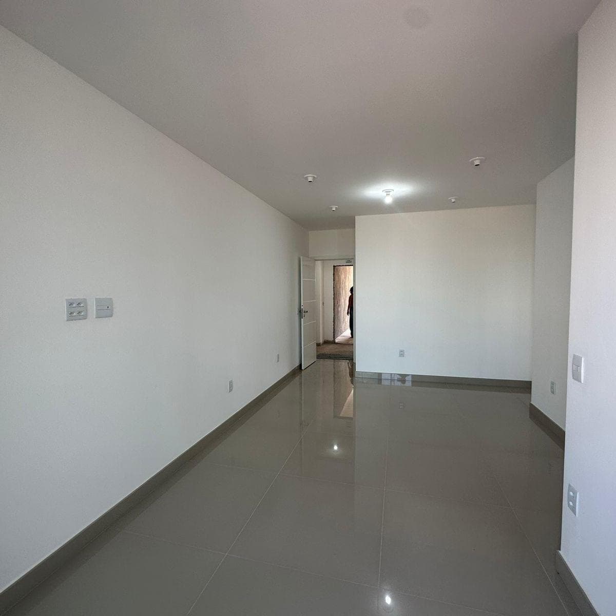 Sala de estar com piso em porcelanato claro e paredes brancas