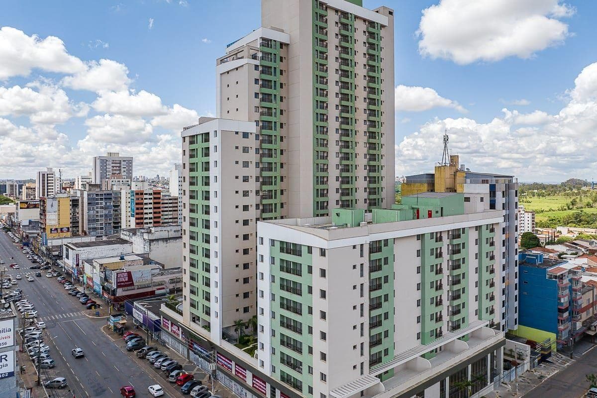 Vista aérea e lateral do edifício residencial com rua movimentada e cidade ao fundo