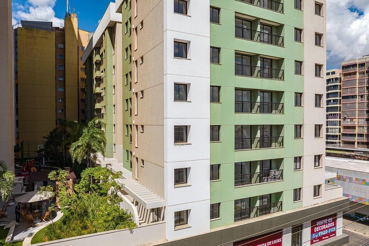 Fachada externa do edifício residencial com pintura em tons de verde, branco e bege.