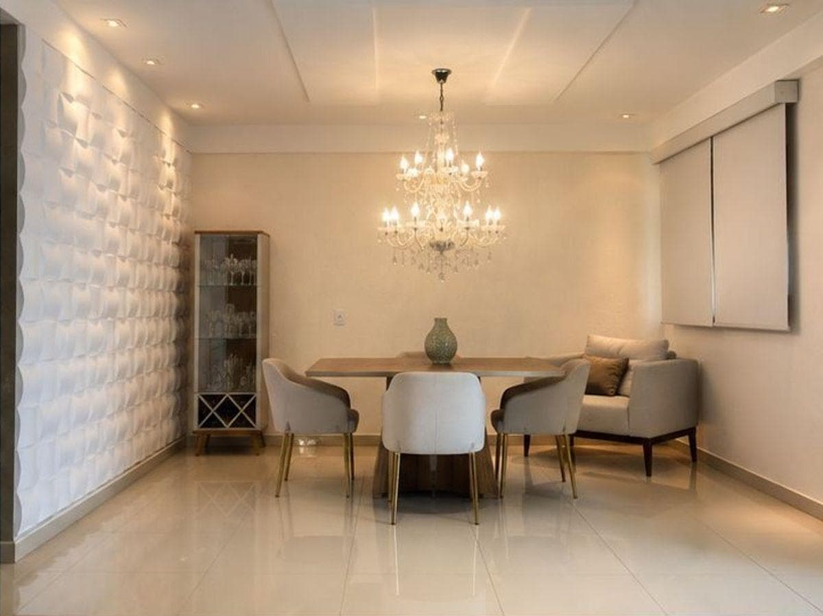 Sala de jantar integrada com mesa, cadeiras estofadas, lustre pendente e parede decorada em 3D.