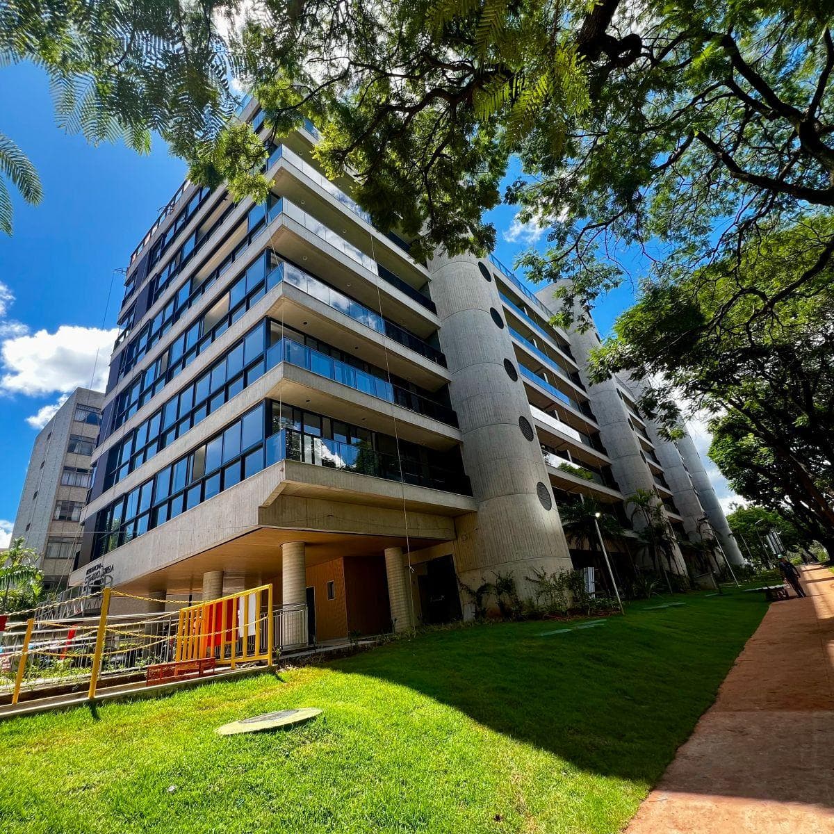 Vista externa da fachada do edifício com área verde.