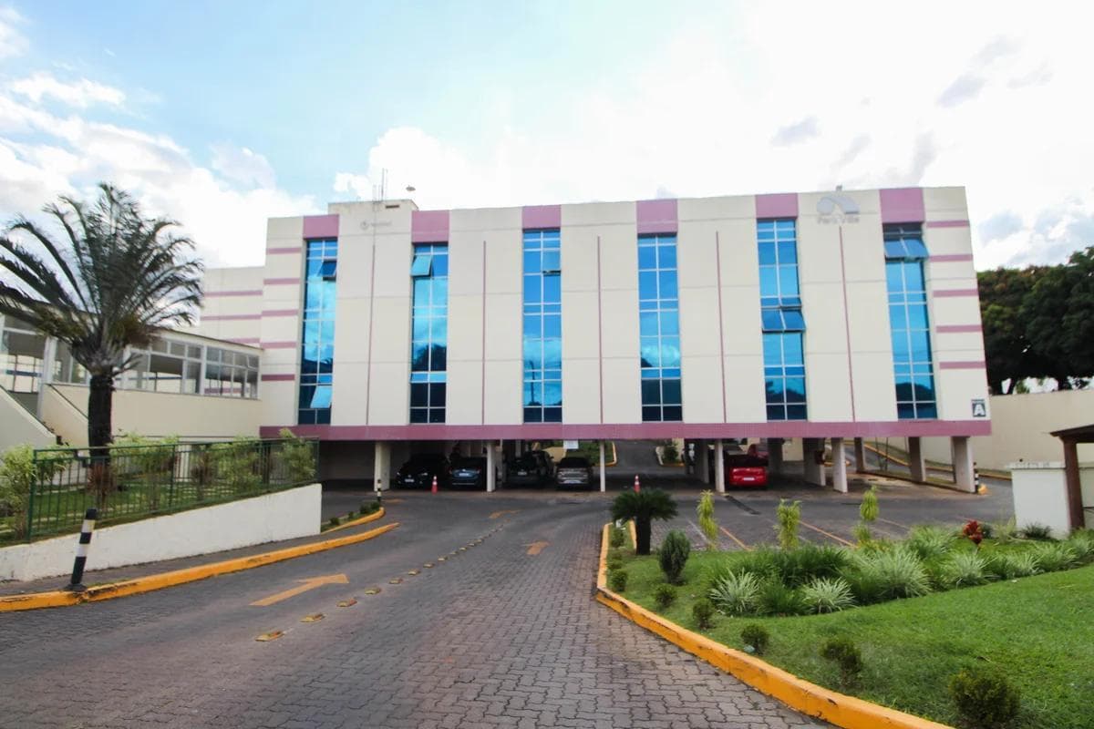 Fachada do edifício residencial com estacionamento coberto e área verde