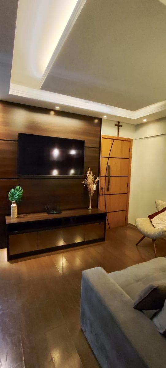 Sala de estar com painel de madeira para TV e sofá cinza.