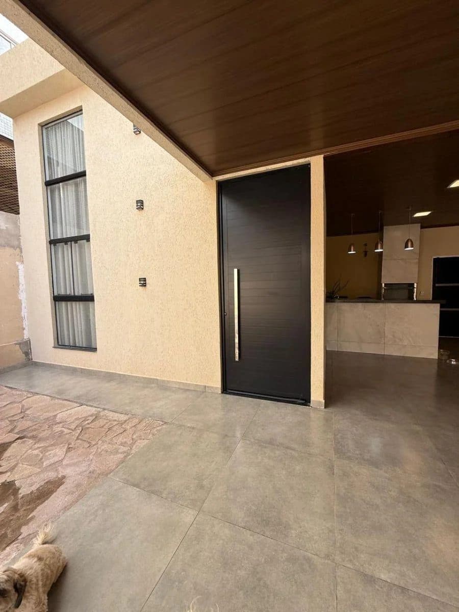 Fachada frontal com porta principal preta, janela lateral e piso em cerâmica.