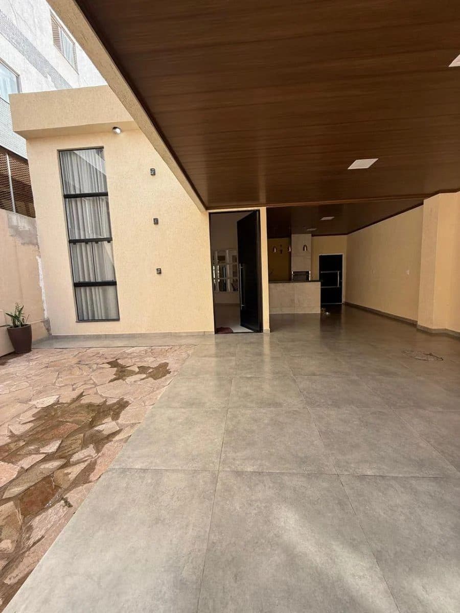Área externa com piso de pedras irregulares, garagem coberta e teto de madeira.