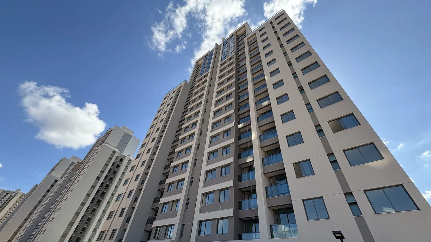 Fachada do edifício residencial em plano contrapicado, mostrando a volumetria e as janelas