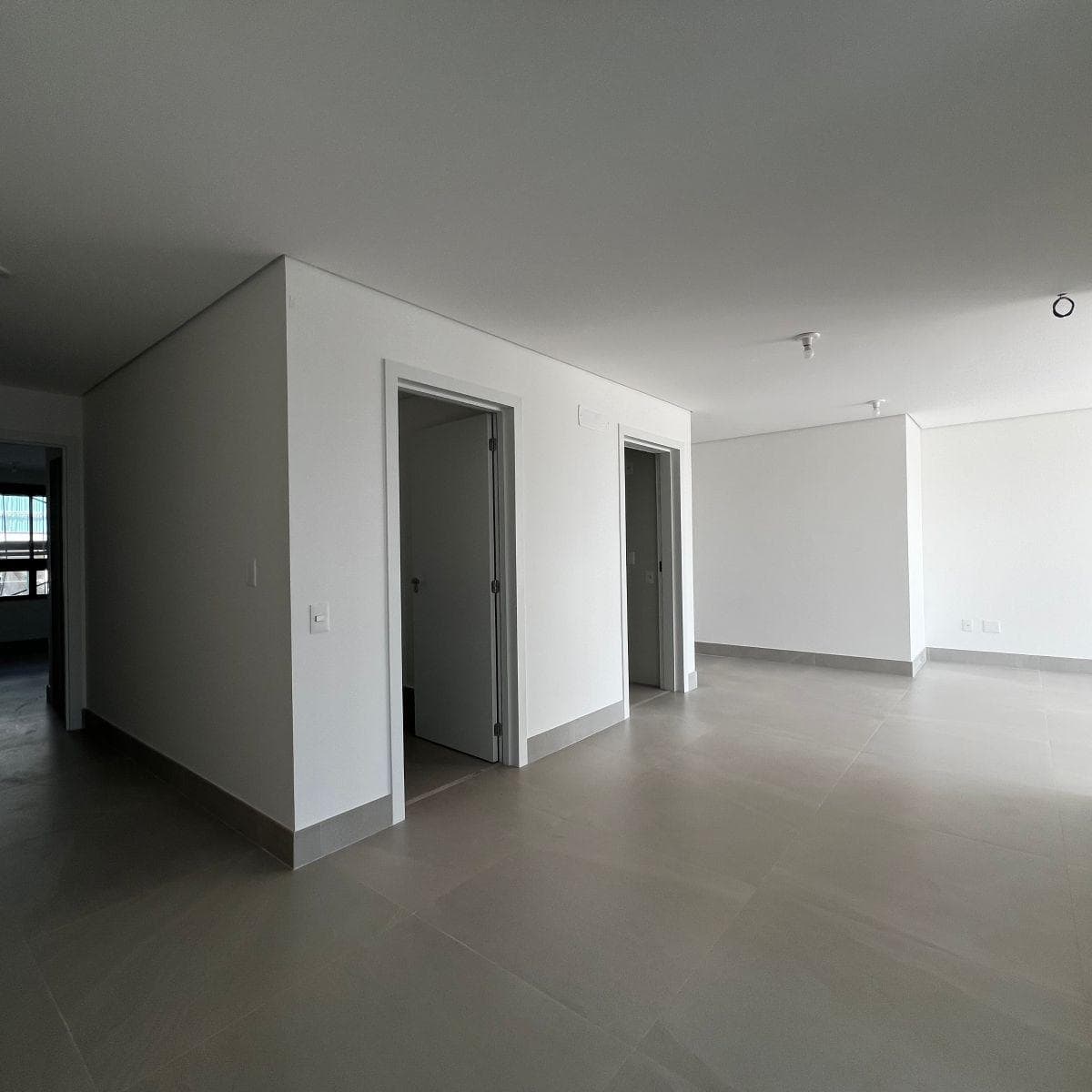 Sala ampla com piso em porcelanato claro e portas internas brancas