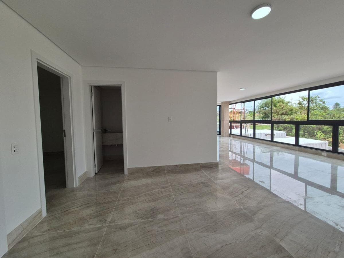 Sala ampla e iluminada com piso em porcelanato polido e grandes janelas com vista externa.