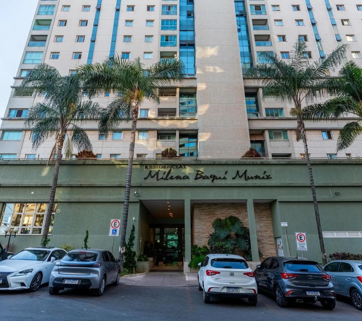 Fachada do edifício residencial com portaria, veículos estacionados e palmeiras