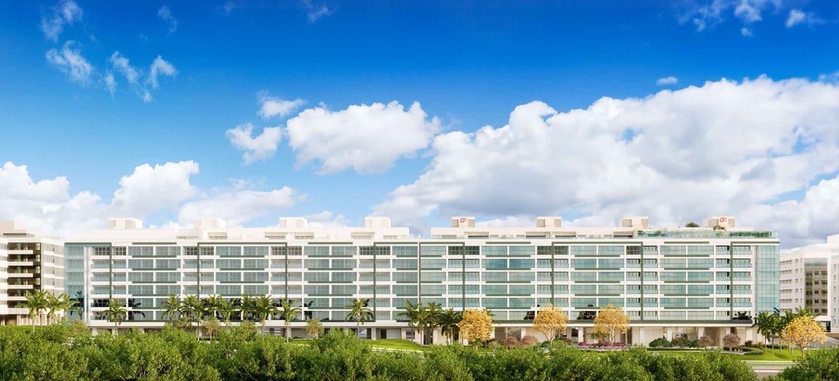 Fachada frontal do edificio residencial com paisagismo e ceu azul