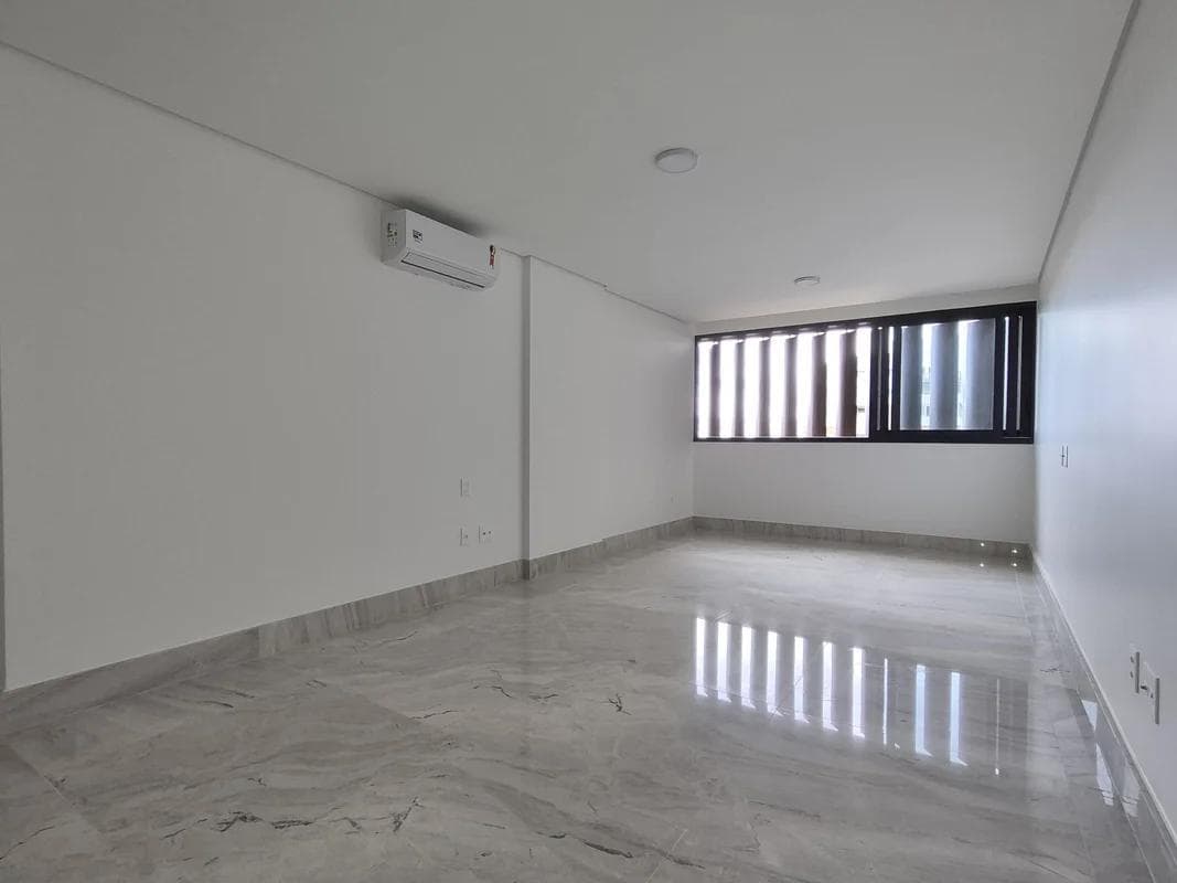 Sala ampla com piso em tom claro e ar-condicionado instalado