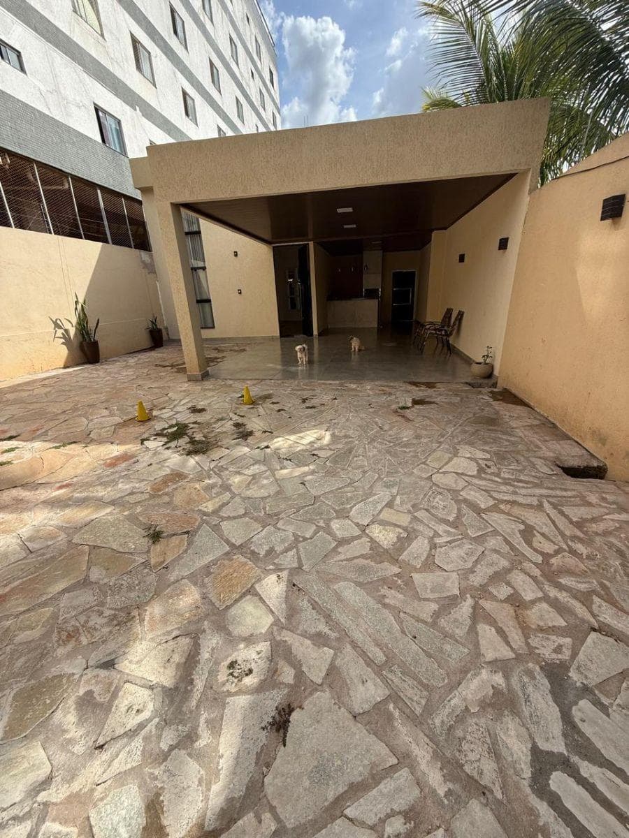 Fachada da casa com garagem coberta, piso em pedras rústicas e área externa.