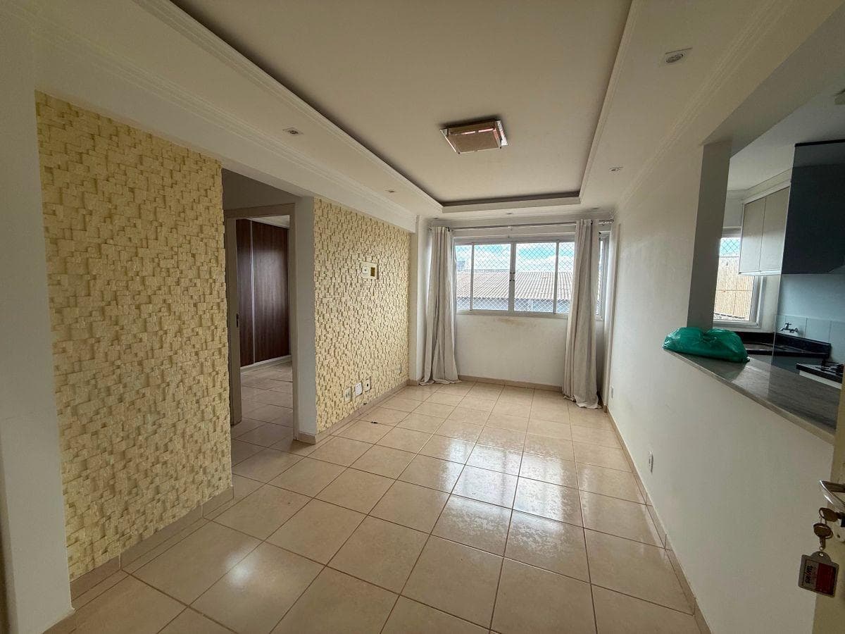 Sala de estar com parede revestida em pedra decorativa, teto rebaixado em gesso e janela com cortina.