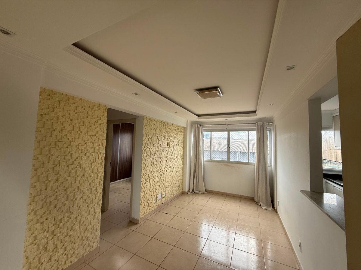 Sala de estar com sanca de gesso no teto, parede com revestimento texturizado e janela com cortinas.