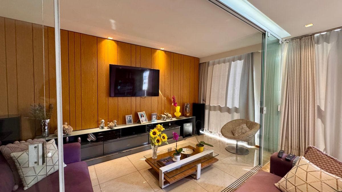 Sala de estar com painel ripado em madeira, TV e sofá roxo.