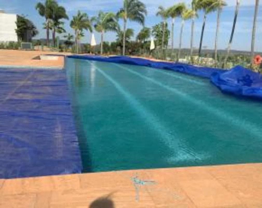Piscina com borda e capa de protecao azul proxima a area verde