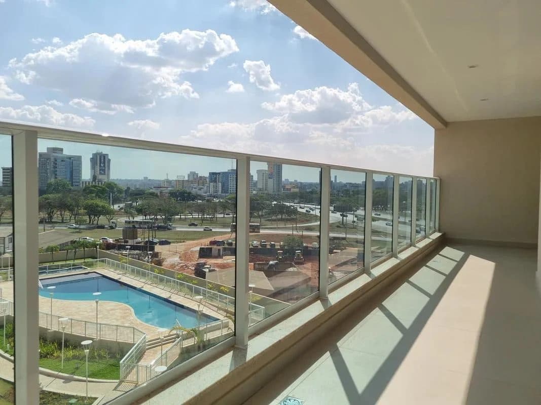 Varanda espaçosa com guarda-corpo de vidro e vista para a área externa.