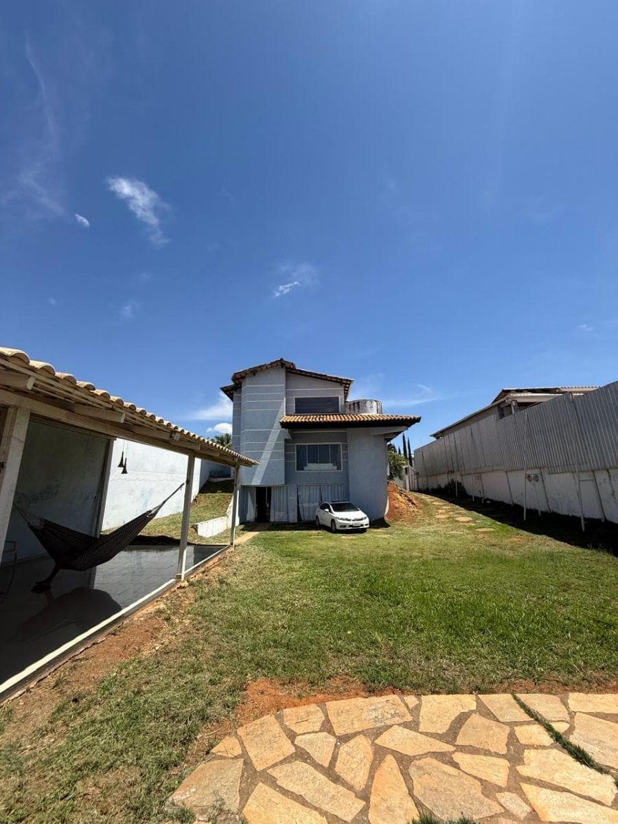 Fachada externa da casa com pintura azul, telhado aparente e gramado.