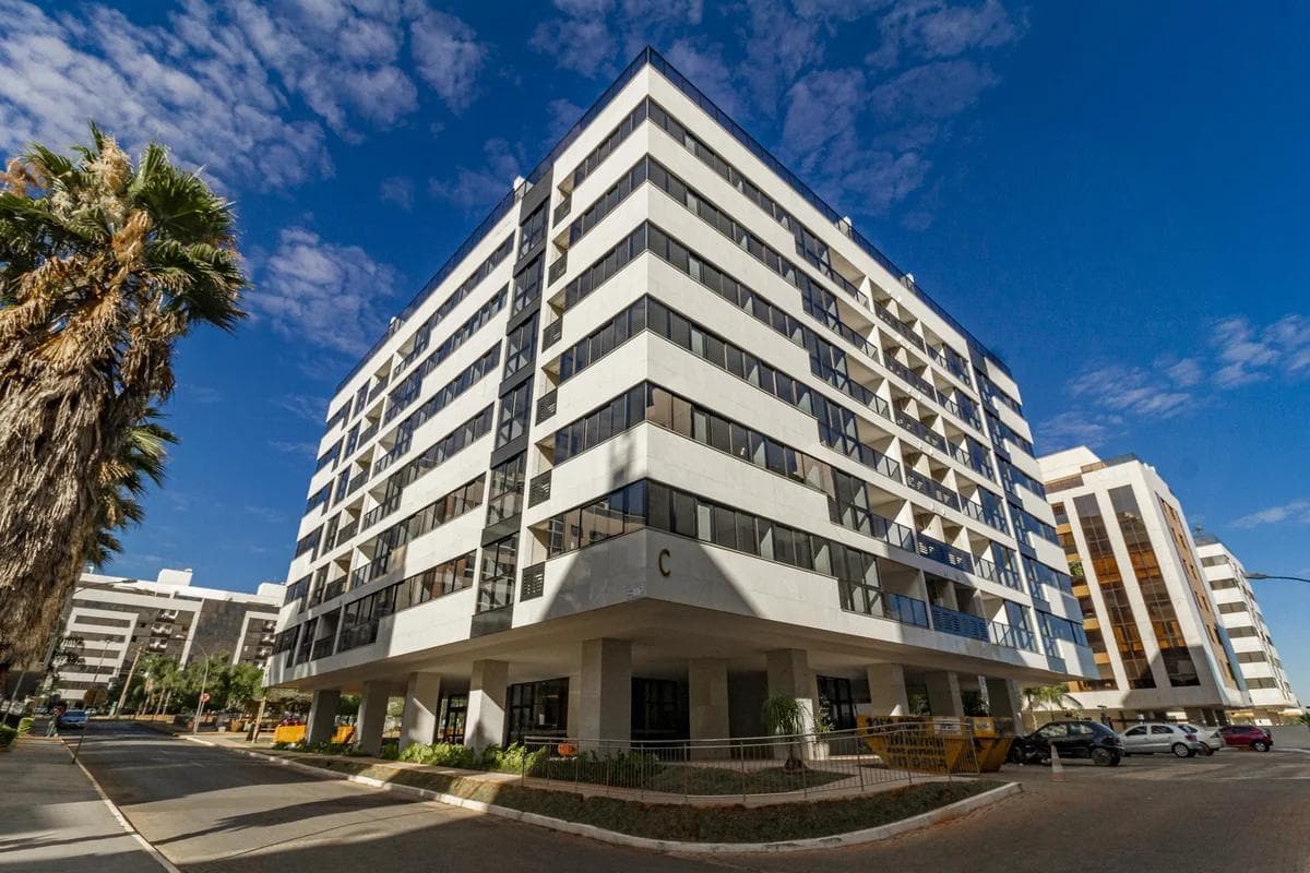 Fachada frontal de prédio residencial moderno com esquadrias escuras e revestimento claro