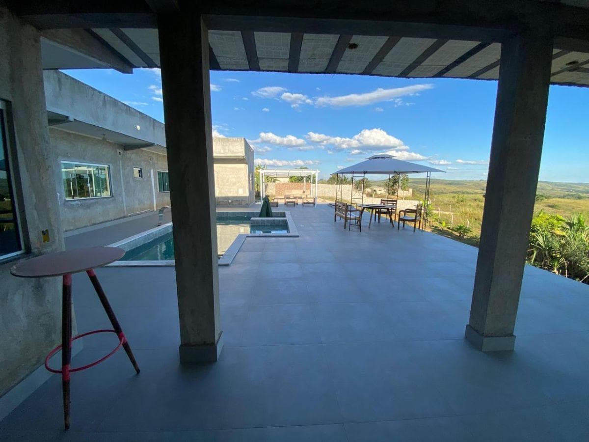 Varanda coberta com piso de cerâmica, pilares de concreto e vista para a piscina.