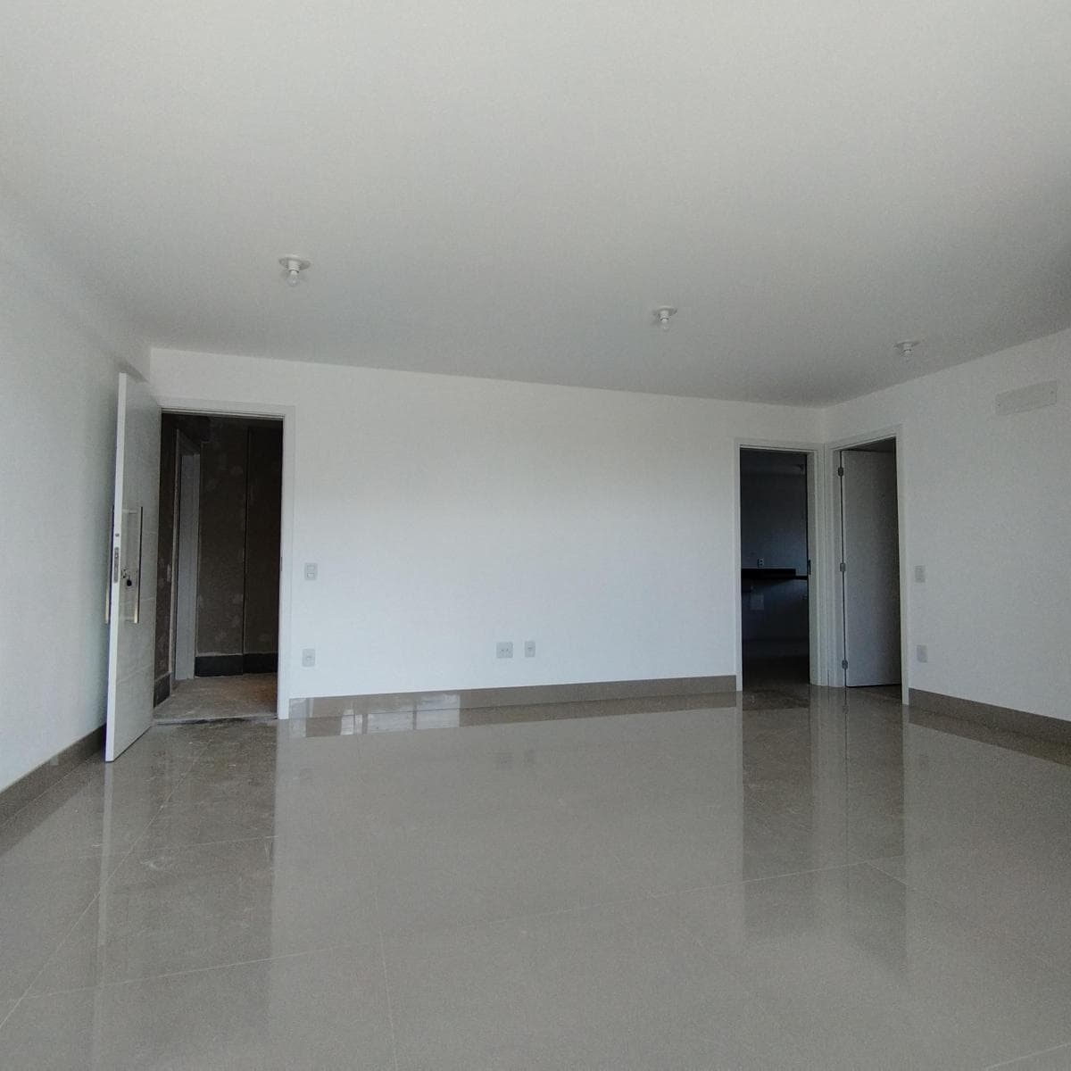 Sala ampla e iluminada com piso em porcelanato claro e paredes brancas.