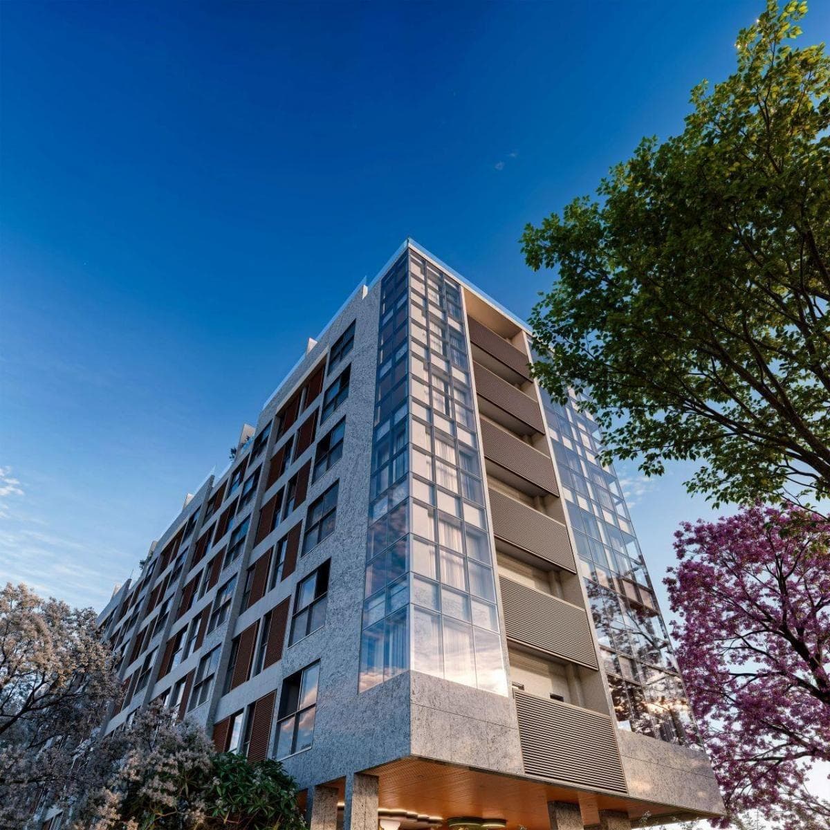 Fachada do edifício residencial com revestimento texturizado e amplas janelas de vidro sob céu azul.