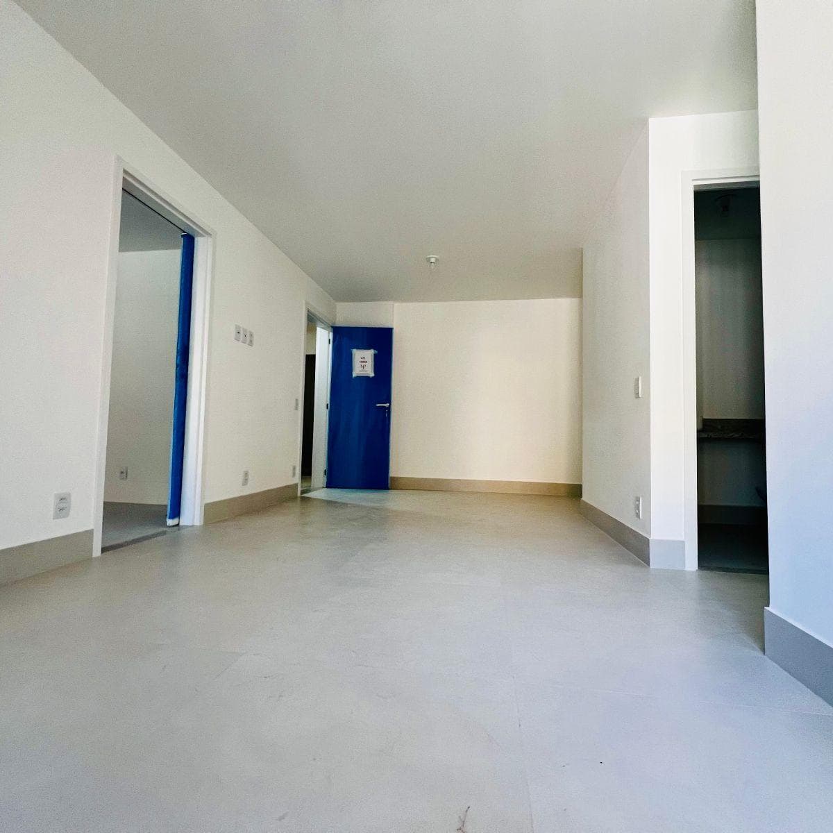 Vista interna da sala com portas para os cômodos e acabamento em branco.