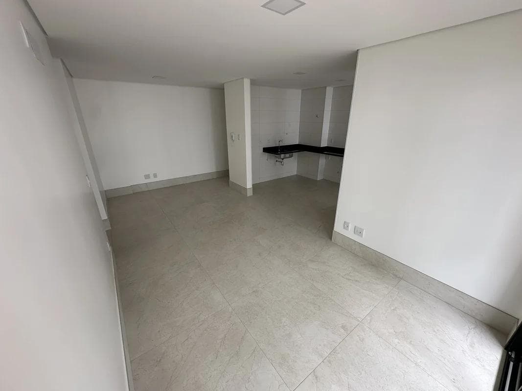 Sala integrada com ponto de cozinha ao fundo e piso revestido em porcelanato.
