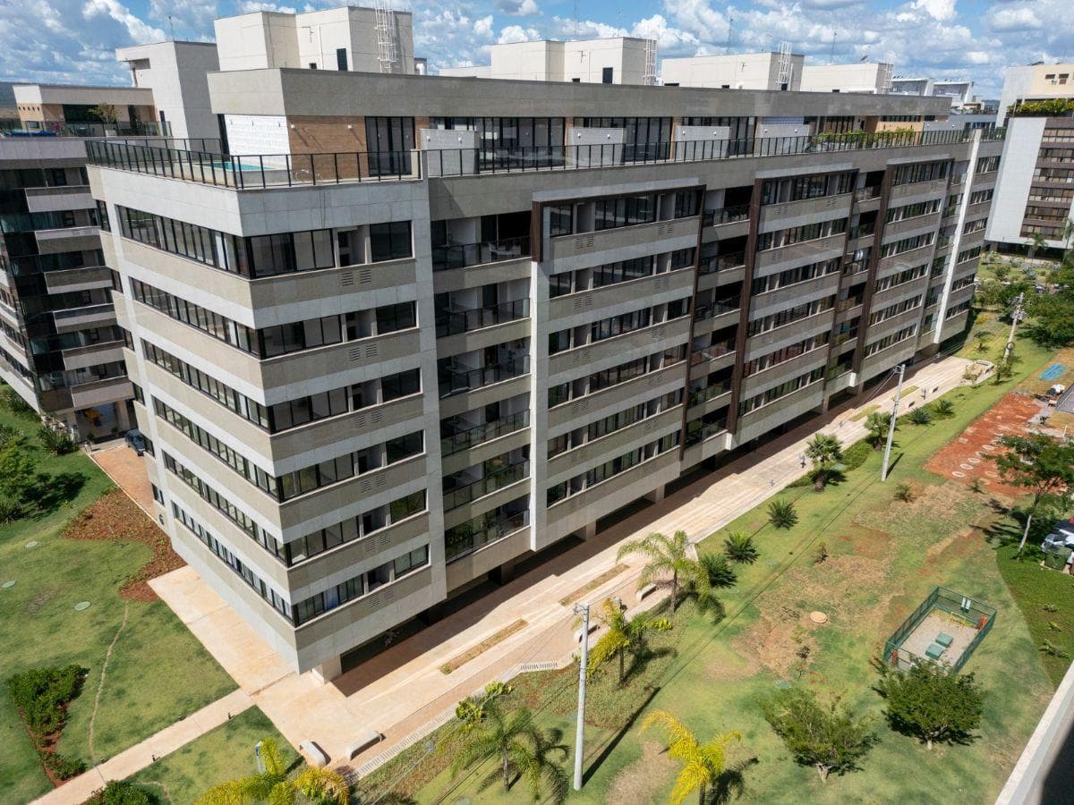 Fachada externa do edificio residencial com varandas e jardim ao redor.