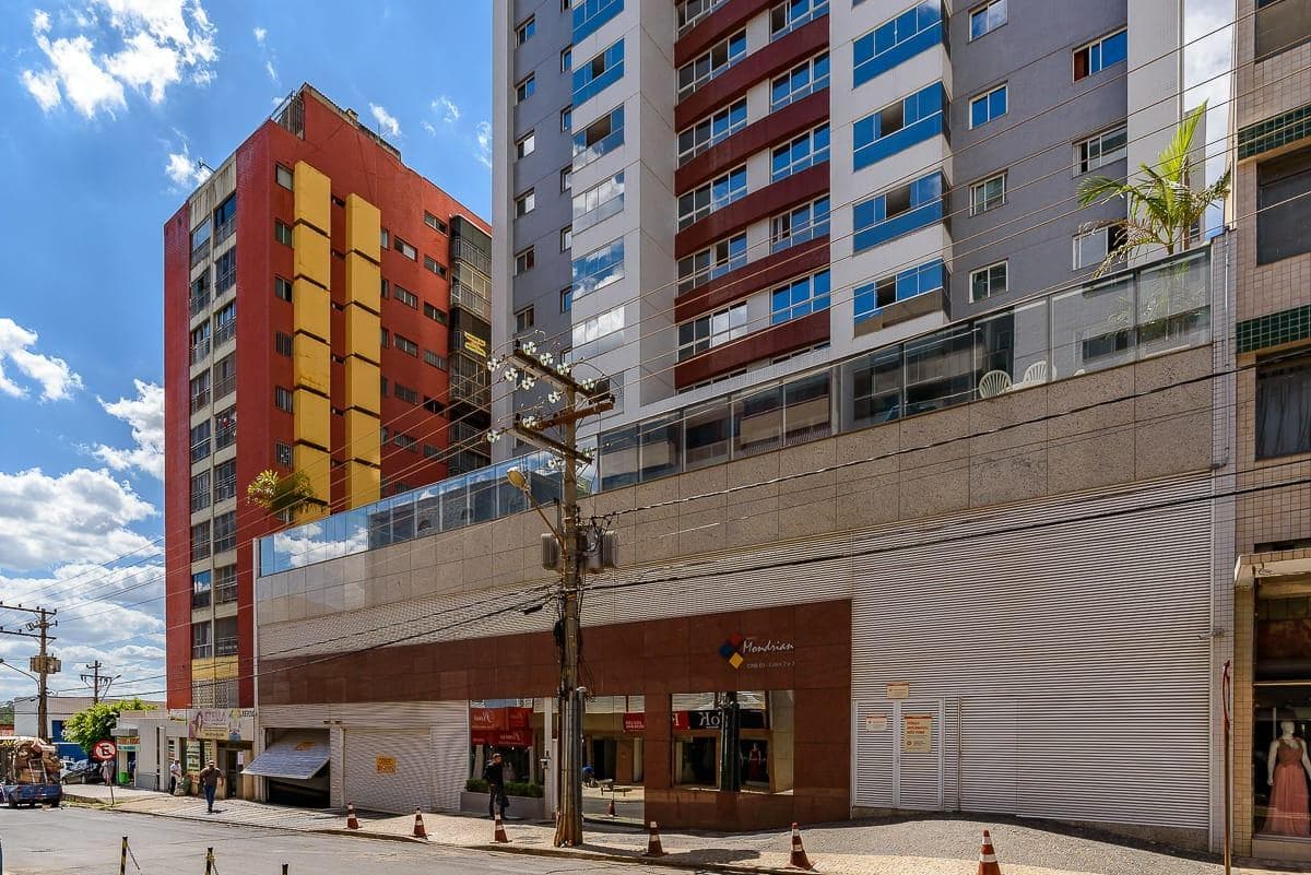 Fachada frontal da entrada do edifício com revestimento em pedra e calçada