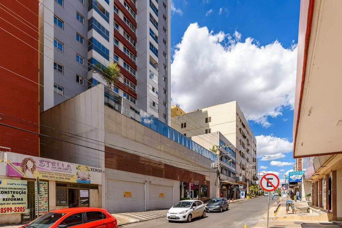 Vista externa da rua com edificacao comercial e predio residencial ao fundo